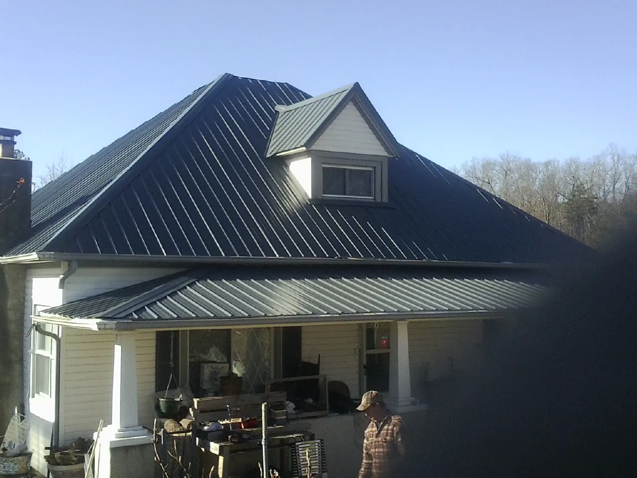 Dark blue standing seam metal roof with a dormer above a front porch in Alton