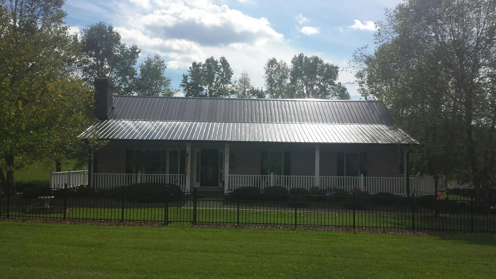 Gray metal roof on a brick ranch with a full width front porch — Gutter Guard Installation work by our crew in Alton